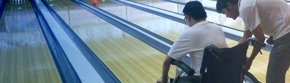 A young man in a wheelchair going bowling.